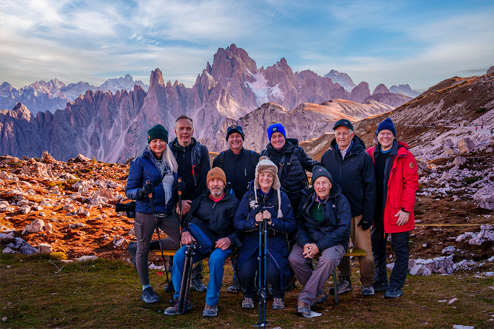 Photography workshop participants posing in front of mountain peaks in the Dolomites during golden hour