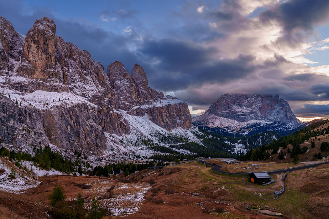 Evening light on snow-dusted cliffs and valley at Passo Gardena in the Dolomites