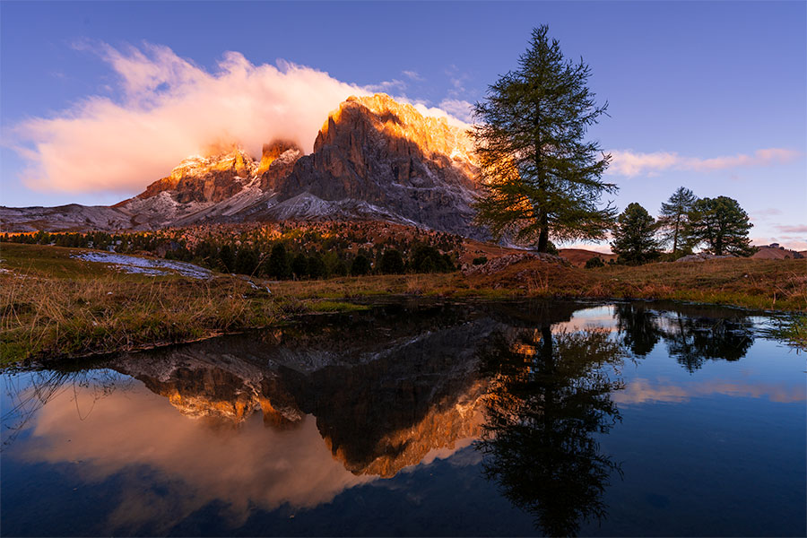 Morning light on peaks at Sella Pass reflected in a small alpine pond in the Dolomites