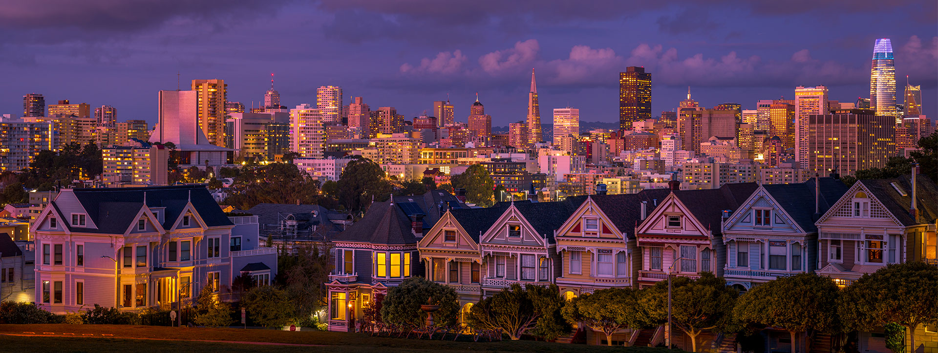 Painted Ladies with the San Francisco skyline illuminated in the evening